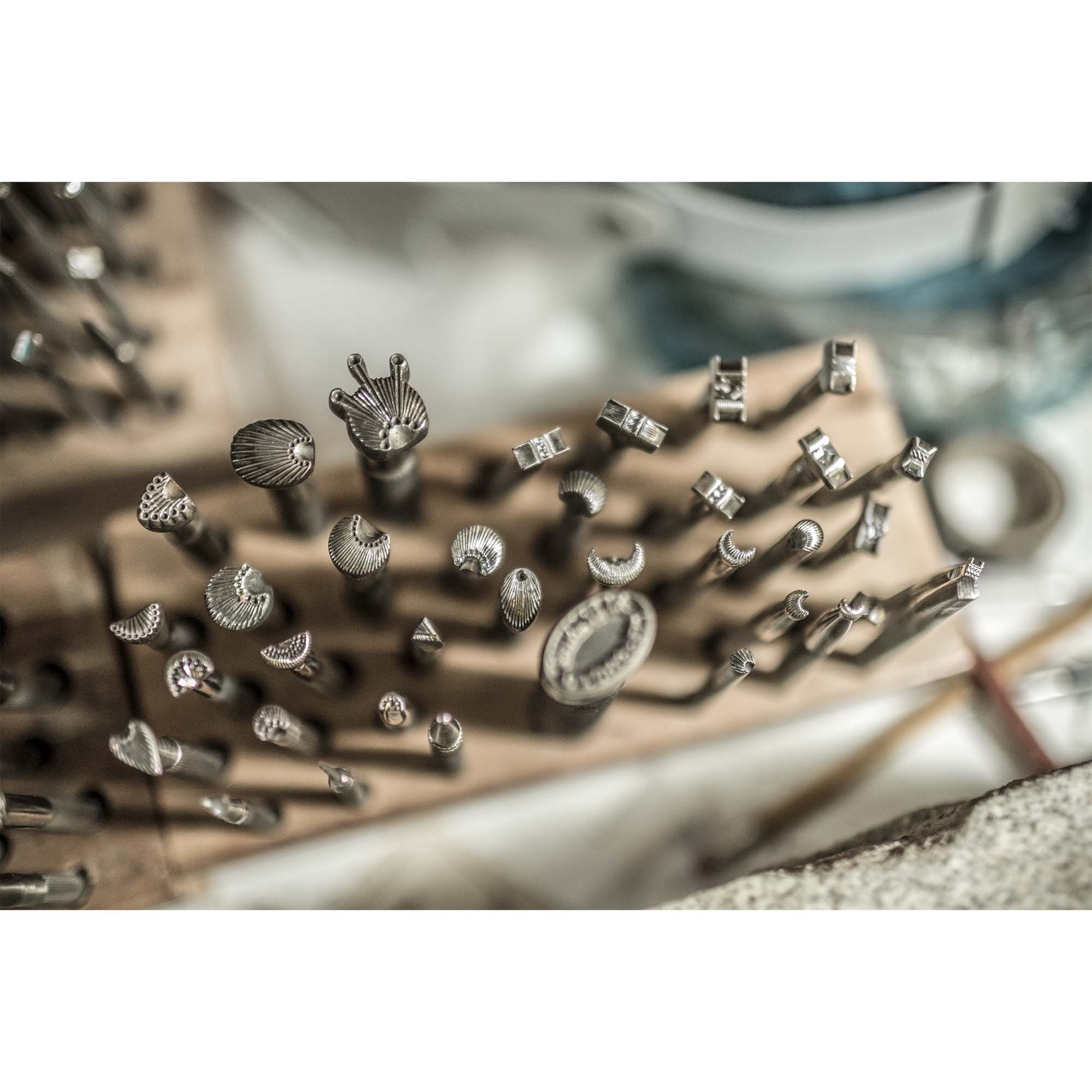 Collection of metal stamps on a wooden block with a blurred background for bootmaking, photo by Tadd Myers